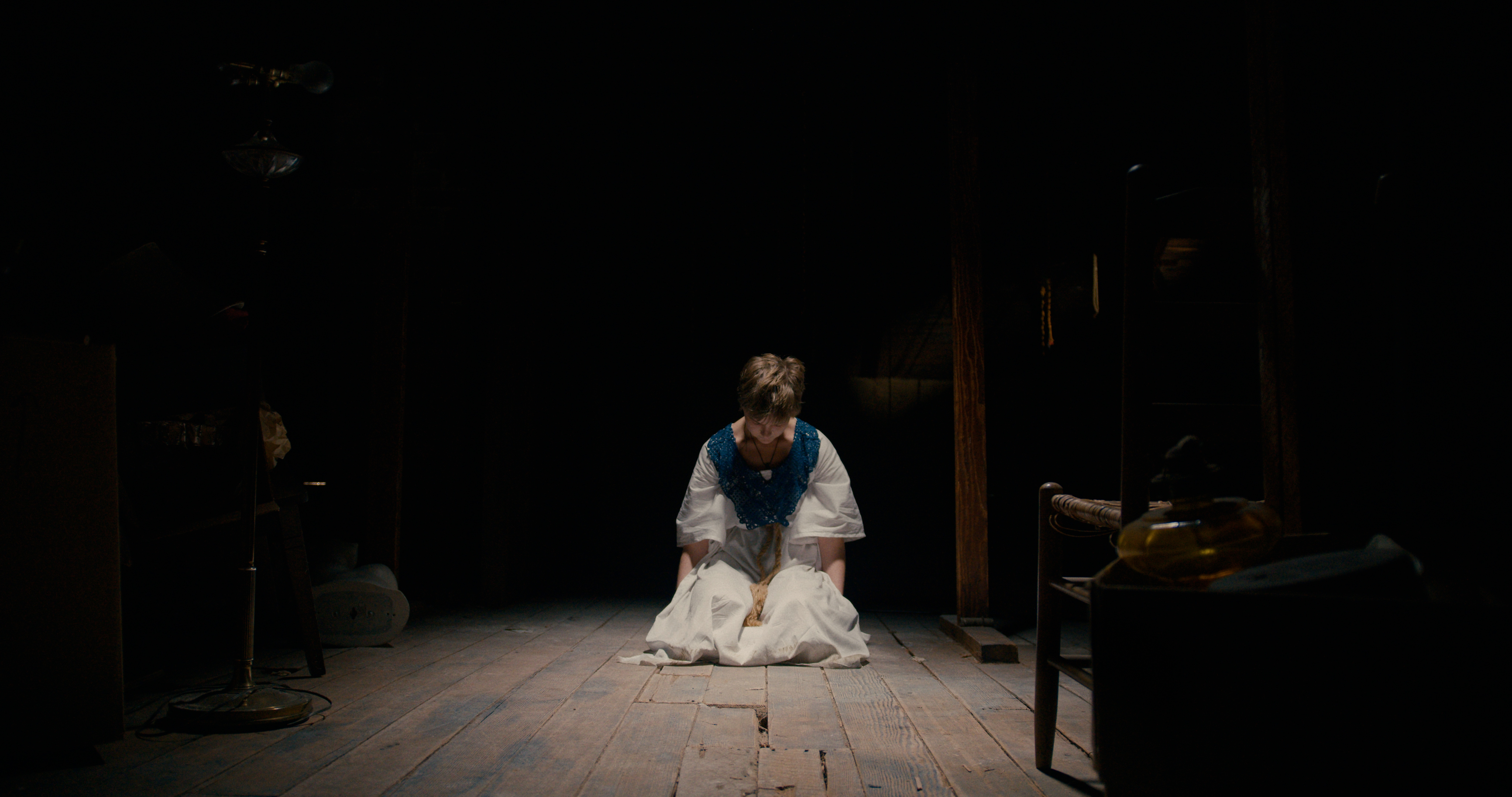 A still from Mind Body Spirit featuring a young woman in a dark room, sitting on the floor.